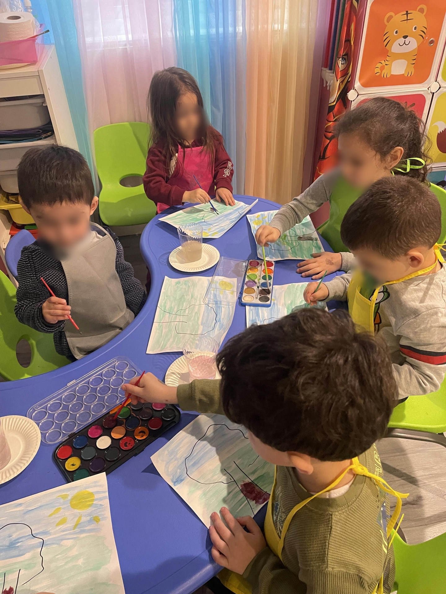 Group of children painting with watercolors around a shared table