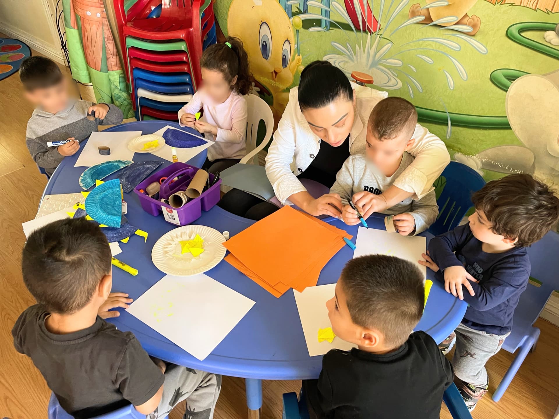 Caregiver guiding children through a paper plate craft project