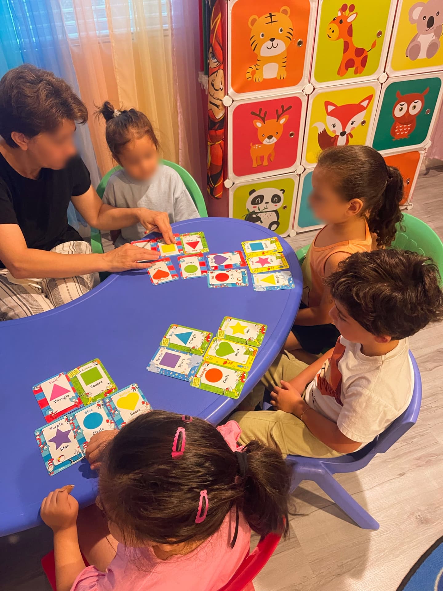 Children learning shapes and colors with flashcards at a table