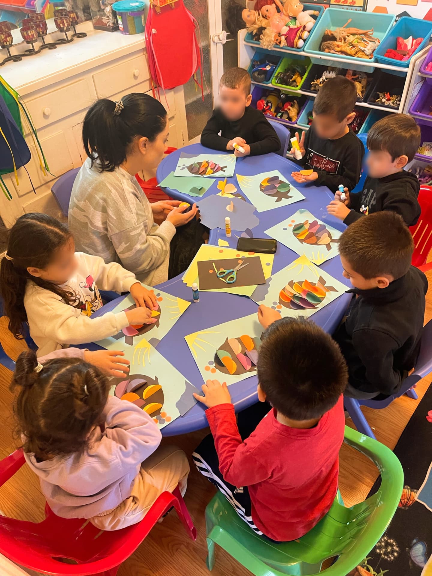 Children making paper turkey collages with a caregiver