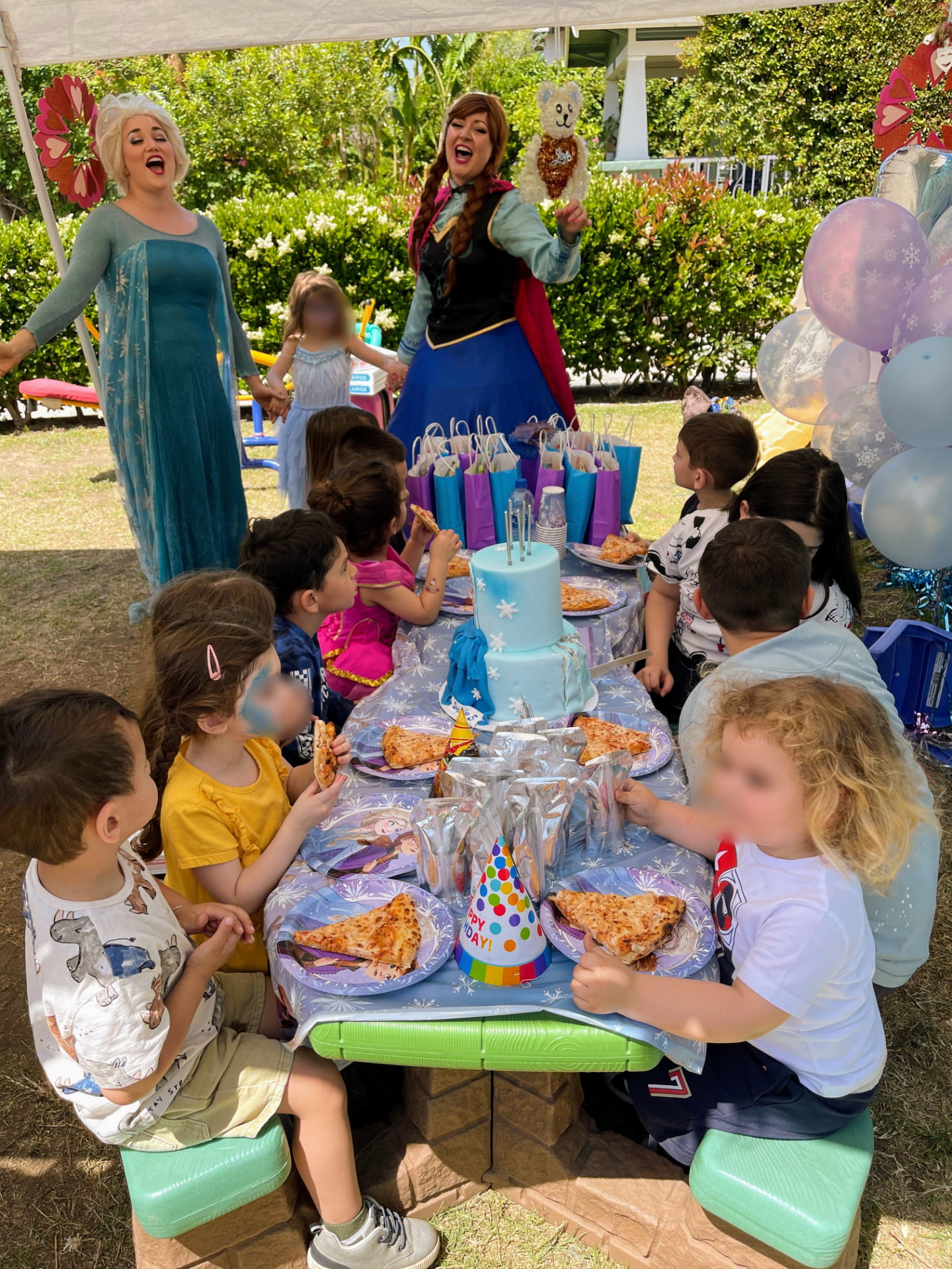 Children enjoying pizza and cake at a Frozen-themed birthday party with costumed characters