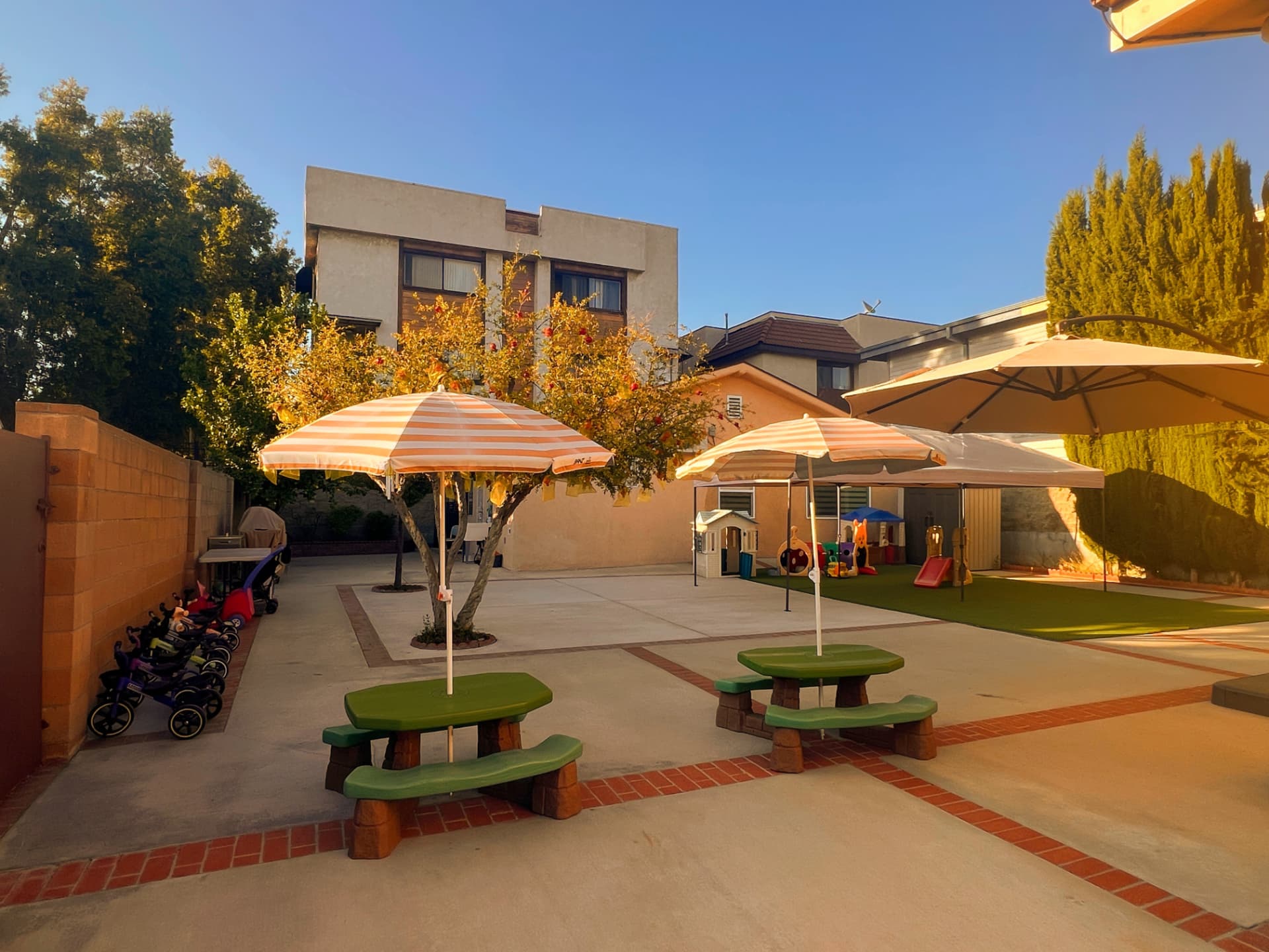 Backyard with shaded picnic tables, umbrellas, and a play area at sunset