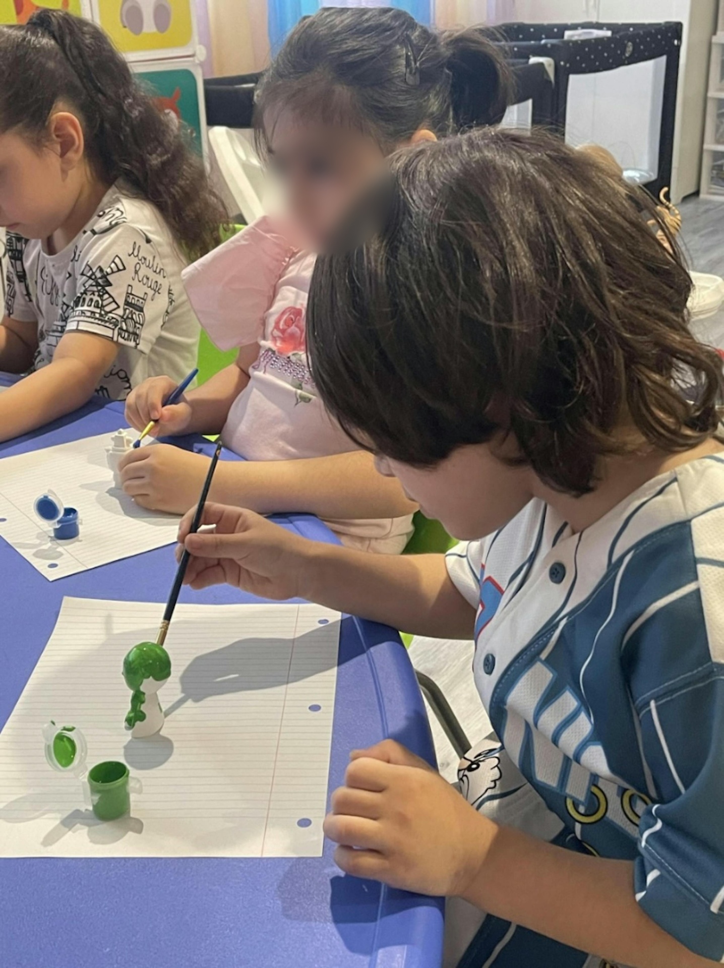 Children carefully painting small figurines together
