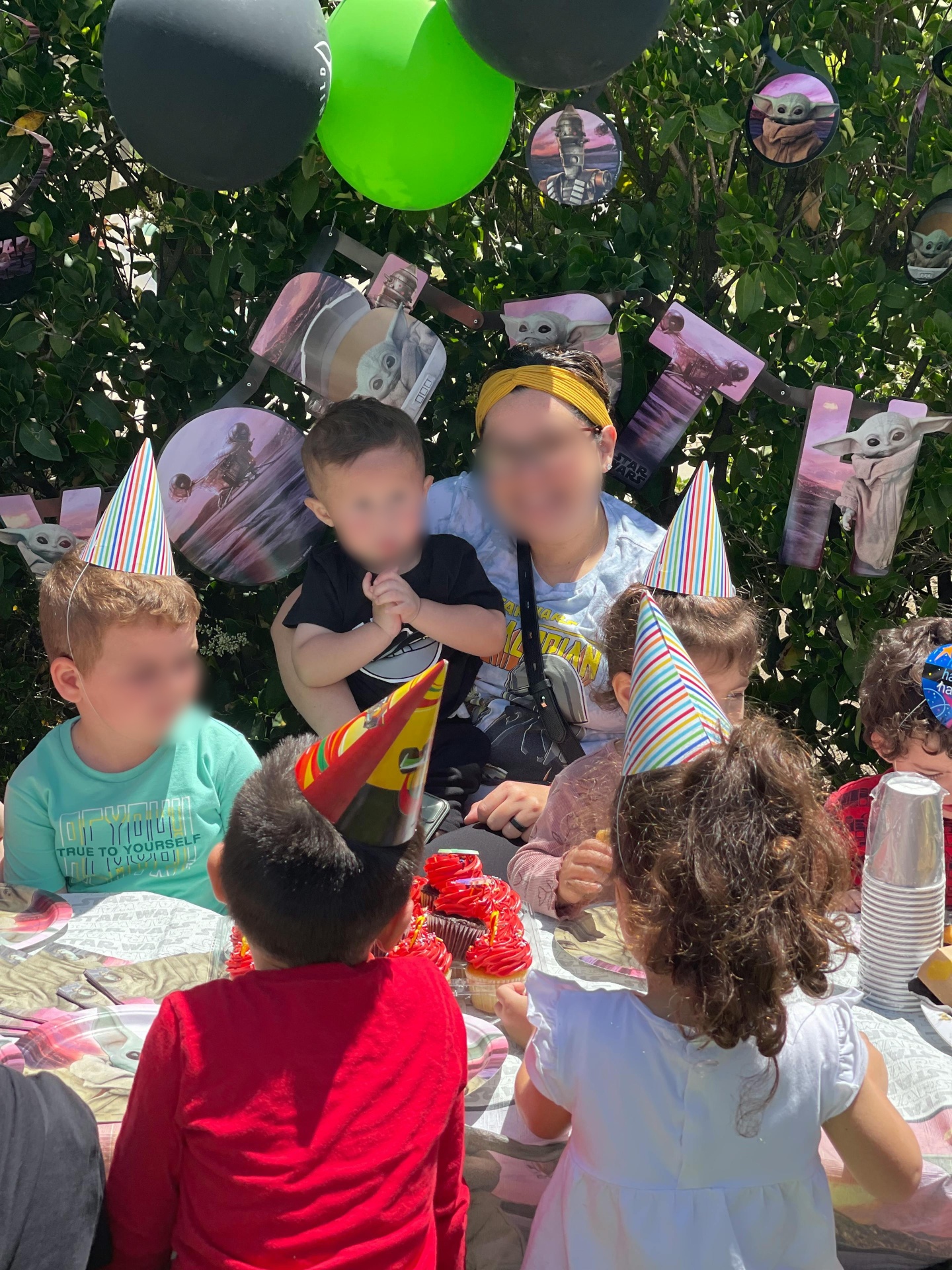 Children wearing party hats celebrating a themed birthday with cupcakes