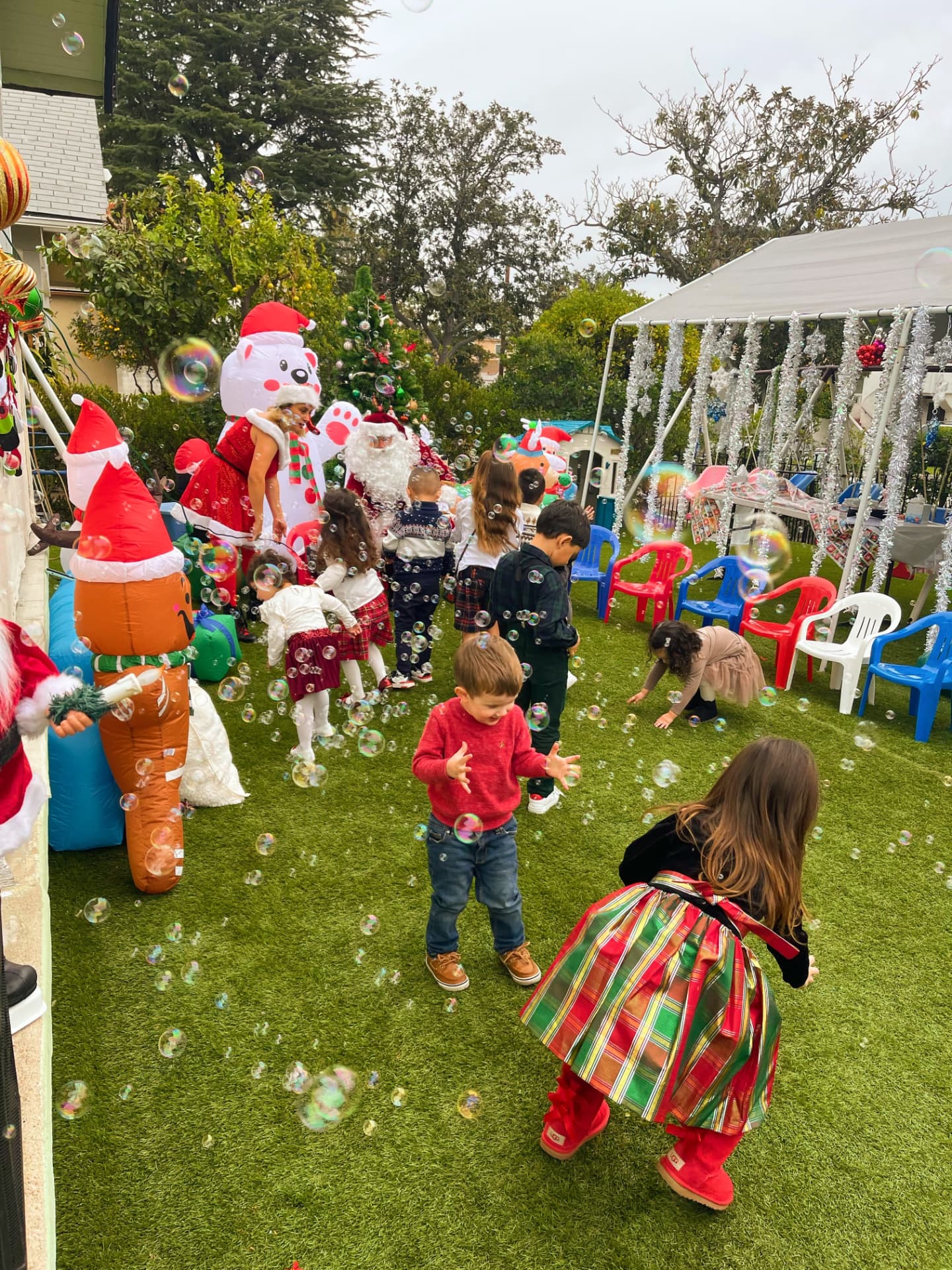 Children running through bubbles at a decorated backyard Christmas party