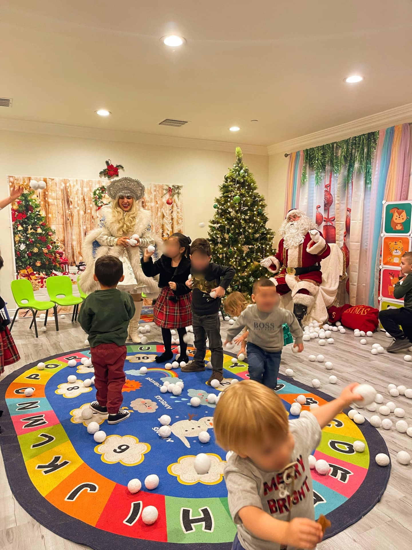 Children playing with indoor snowballs with Santa and the Snow Maiden by the Christmas tree