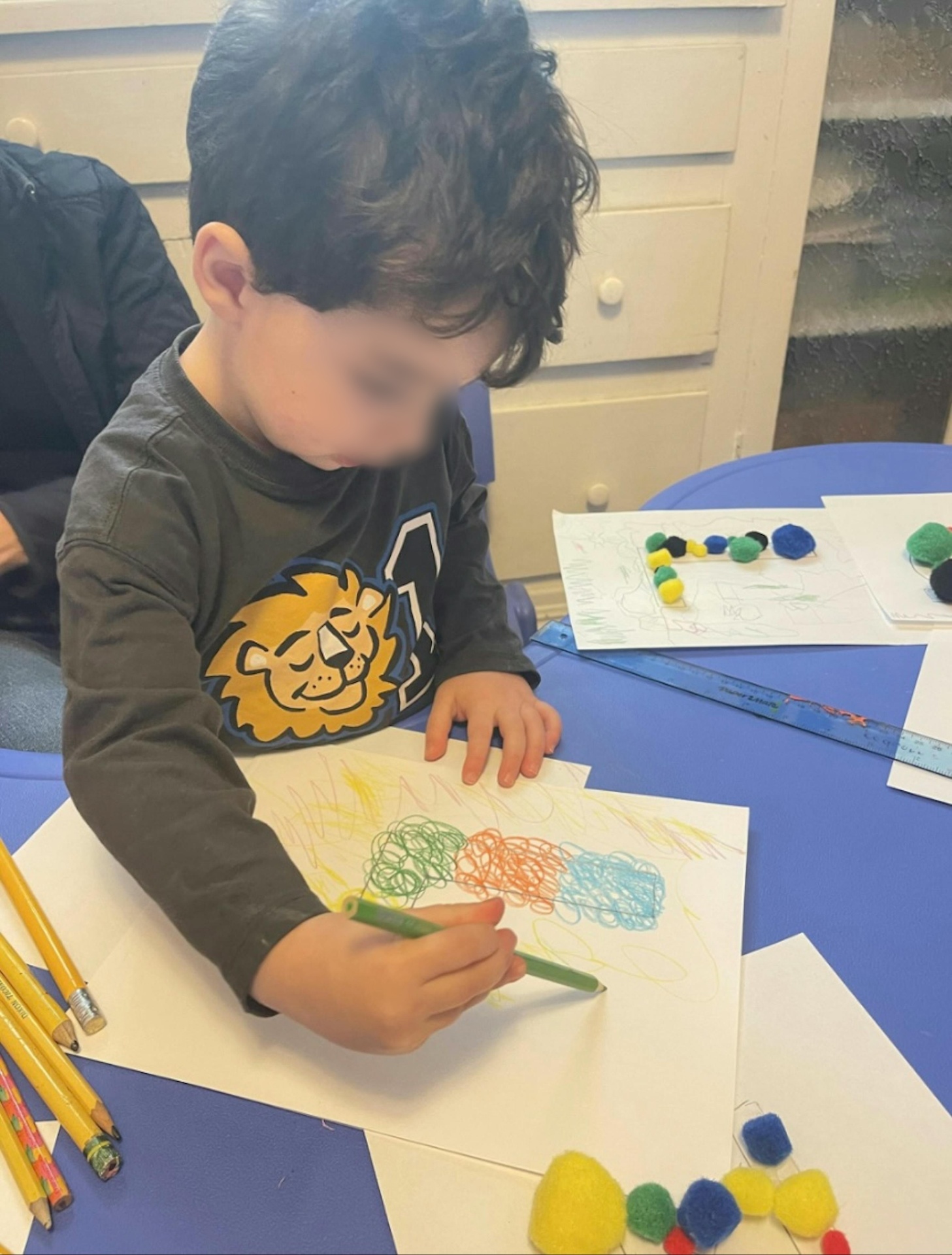Young child concentrating while drawing with colorful crayons