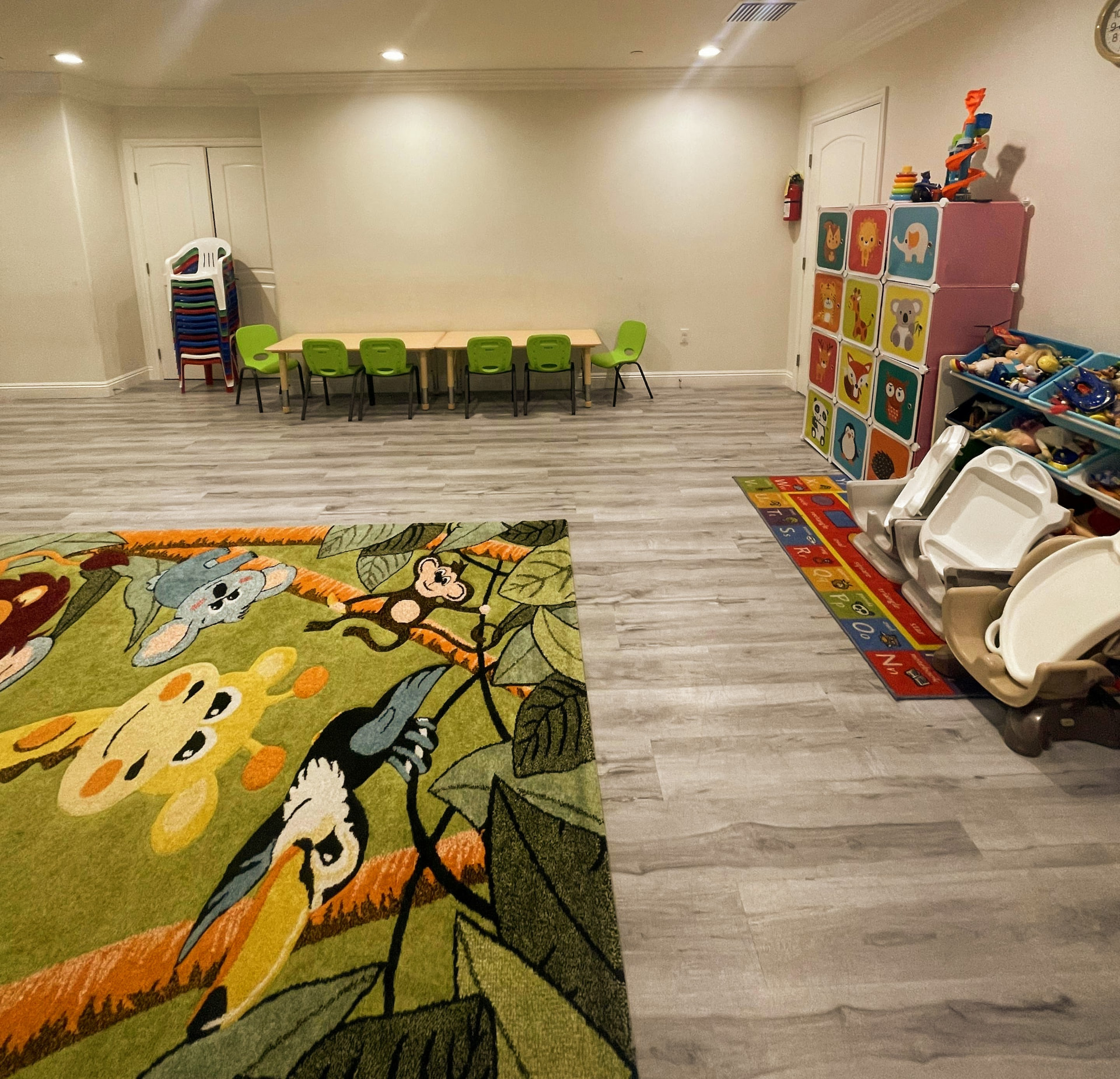 Open playroom with long learning table, stacked chairs, and toy shelves