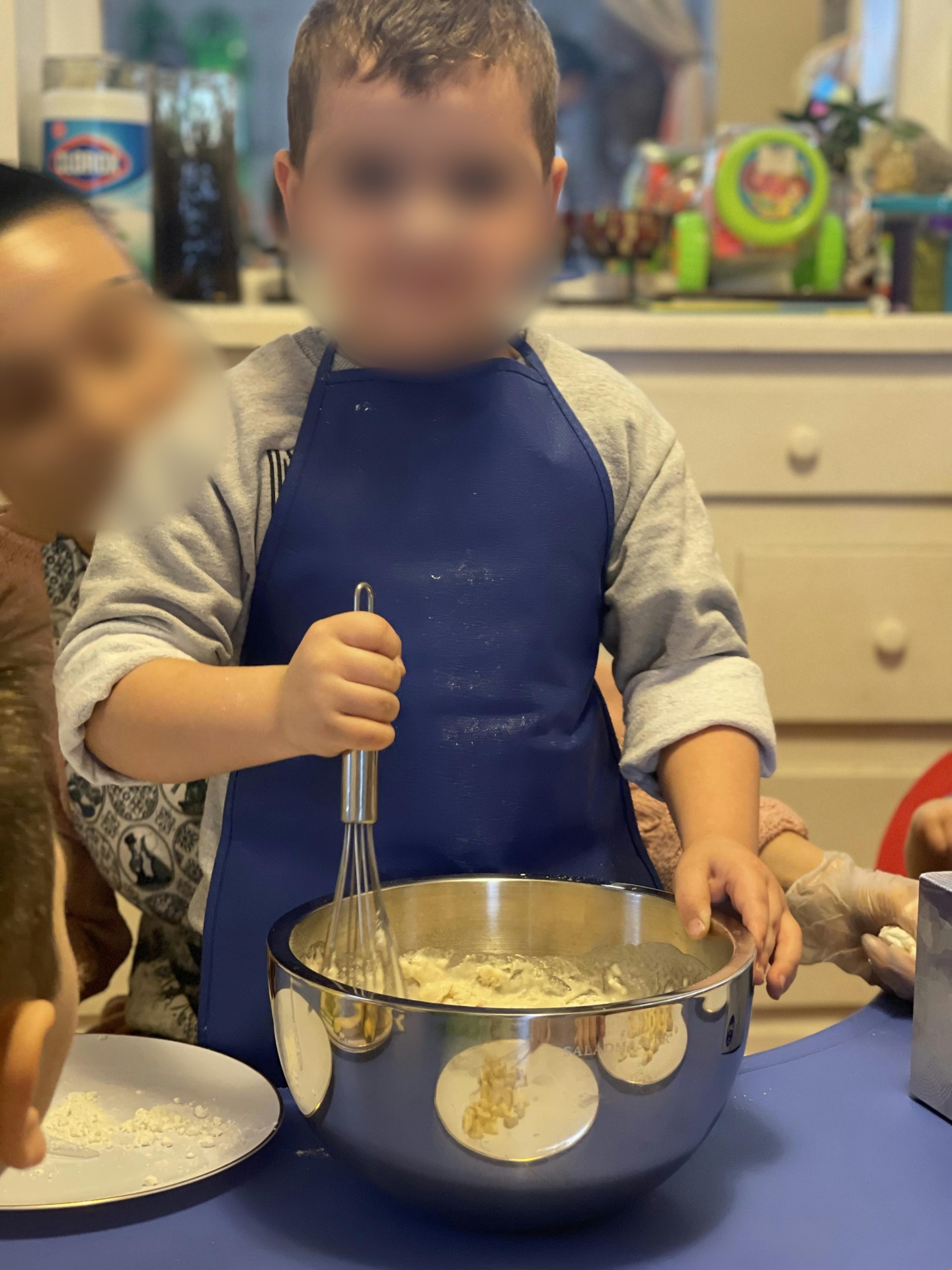 Young child in an apron whisking ingredients in a mixing bowl