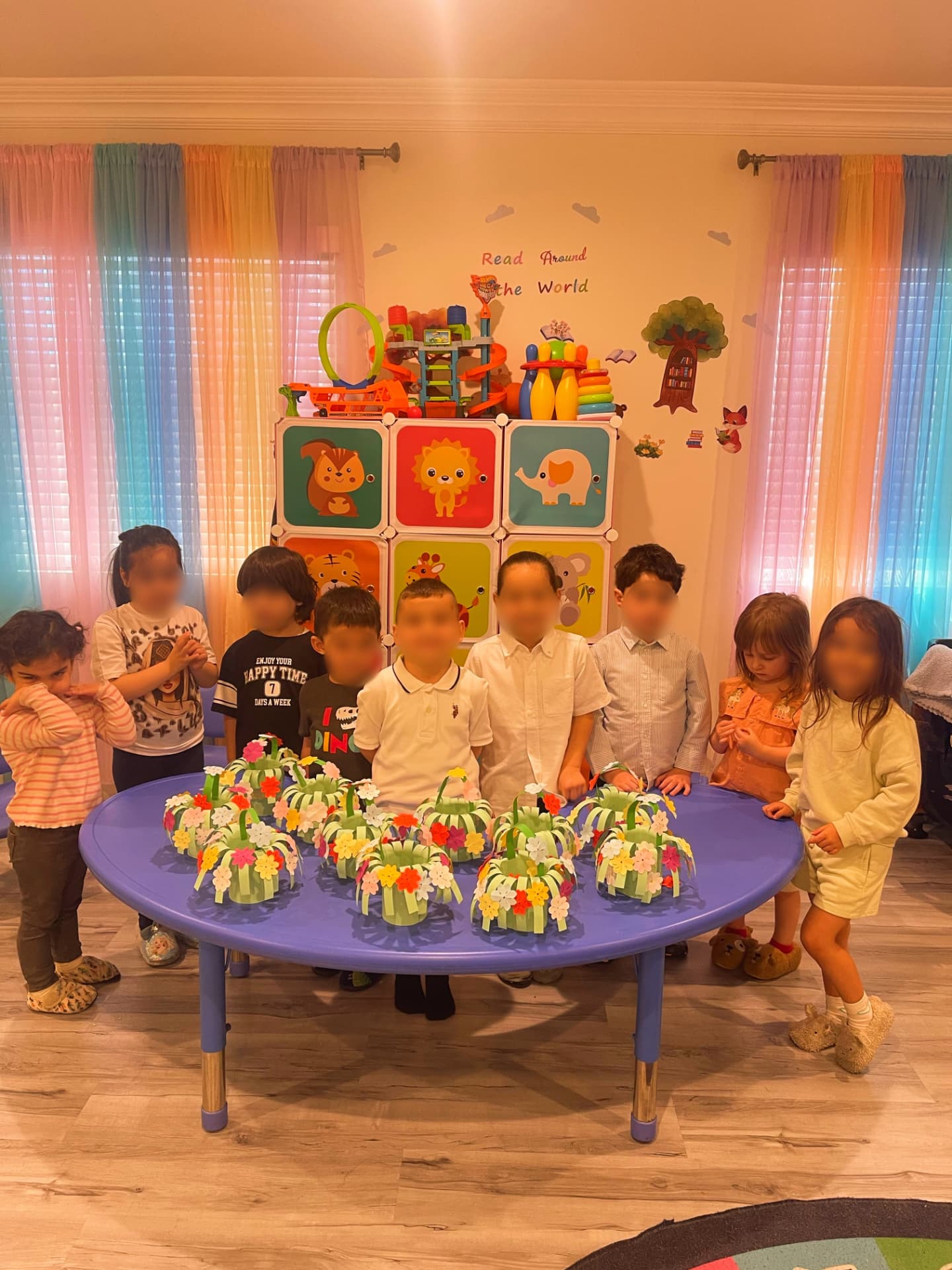 Group of children standing around a table filled with handmade paper flower baskets