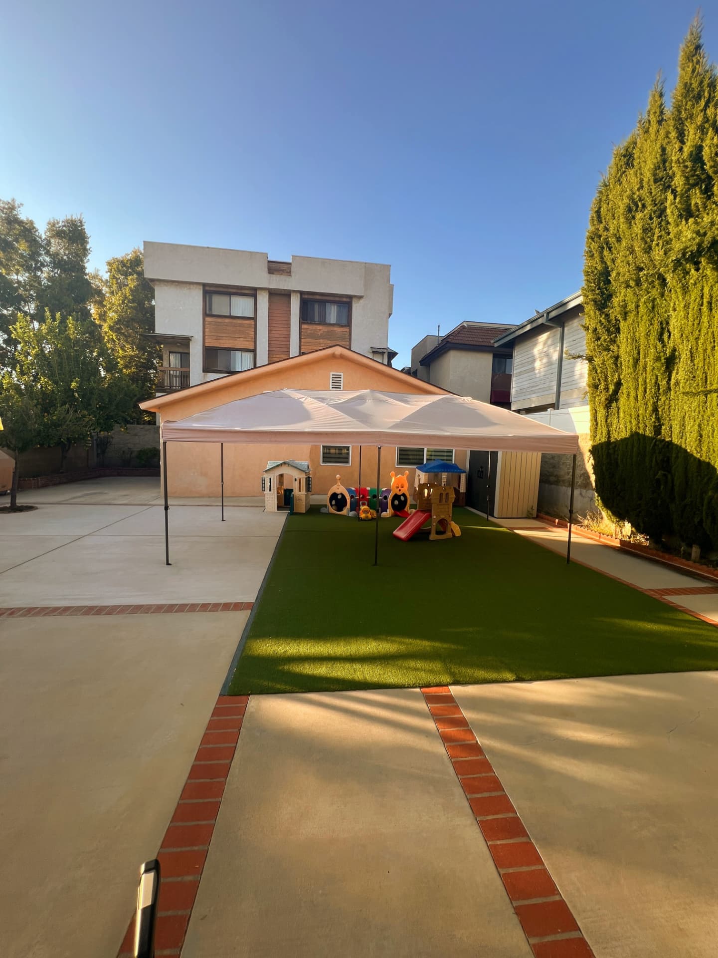 Shaded backyard playground with turf, slide, and playhouse