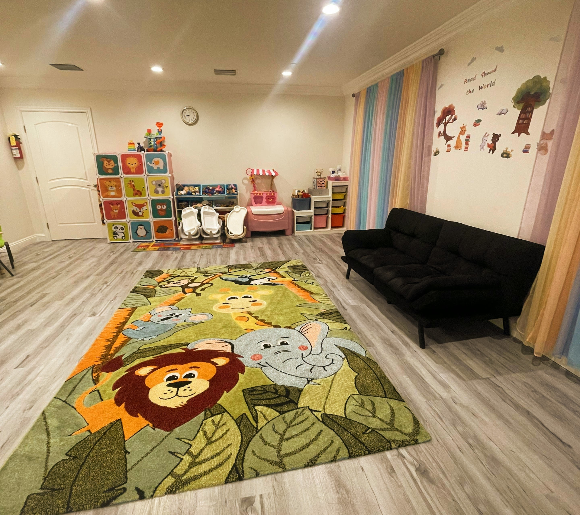 Spacious indoor playroom with a large jungle rug, toy storage, and seating