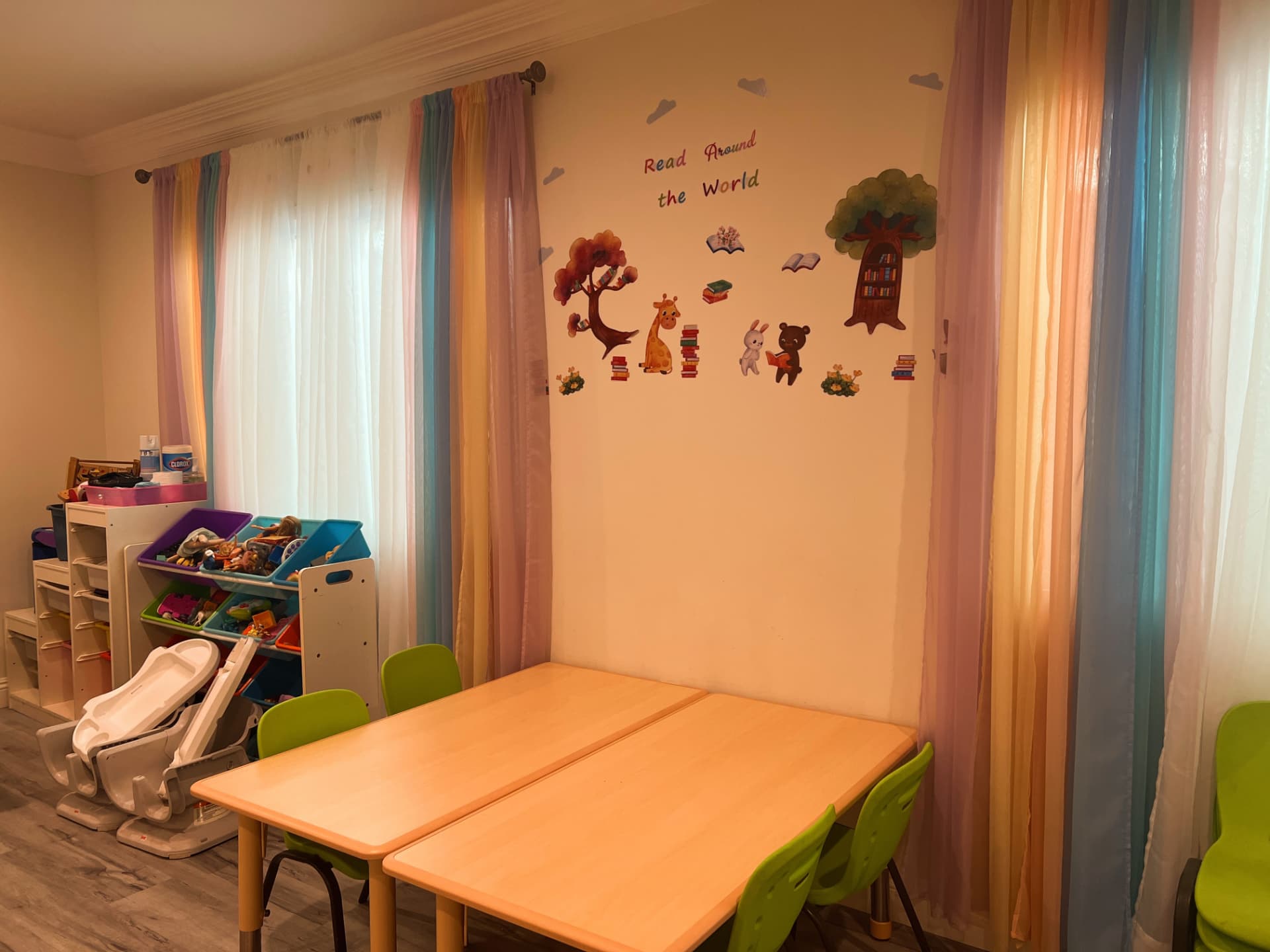 Craft tables and organized toy bins beneath the reading wall decals